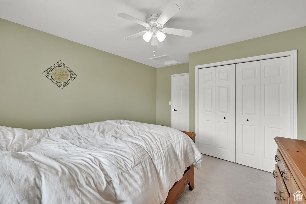 Bedroom featuring light colored carpet, a closet, and a ceiling fan