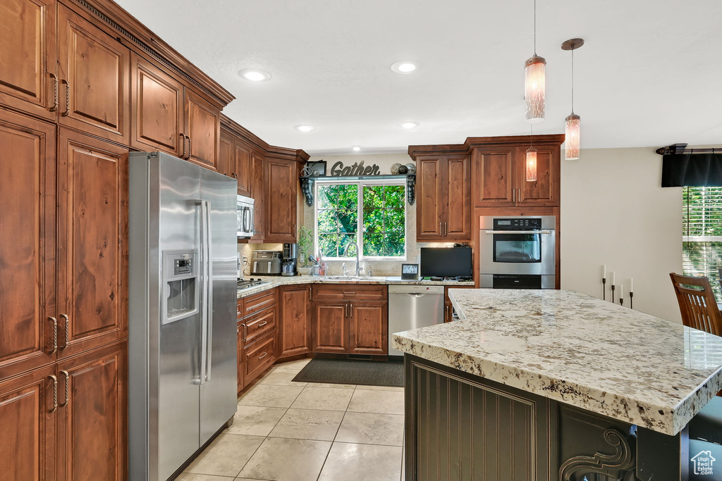 Kitchen with stainless steel appliances, plenty of natural light, a center island, light stone countertops, and recessed lighting
