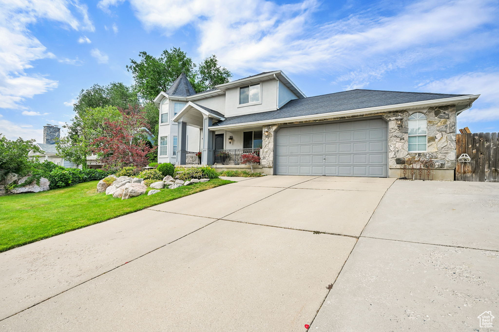 View of front of home with concrete driveway, stone siding, a garage, and stucco siding