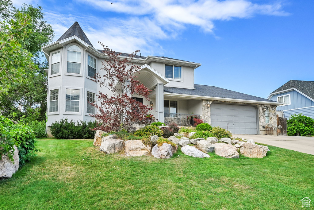 View of front of property with driveway, a front yard, covered porch, and stucco siding