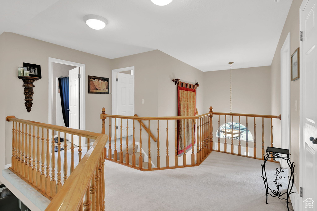Hall featuring an upstairs landing and carpet