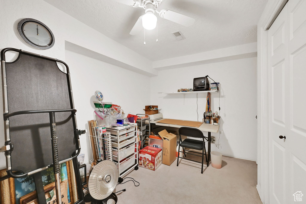 Carpeted home office featuring ceiling fan