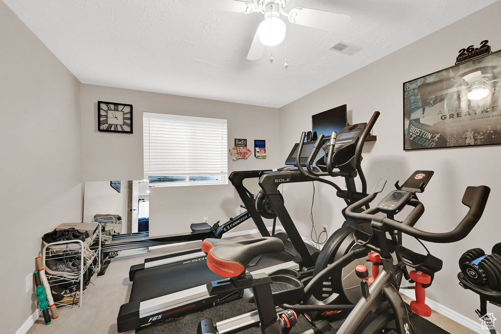 Exercise room with ceiling fan and baseboards