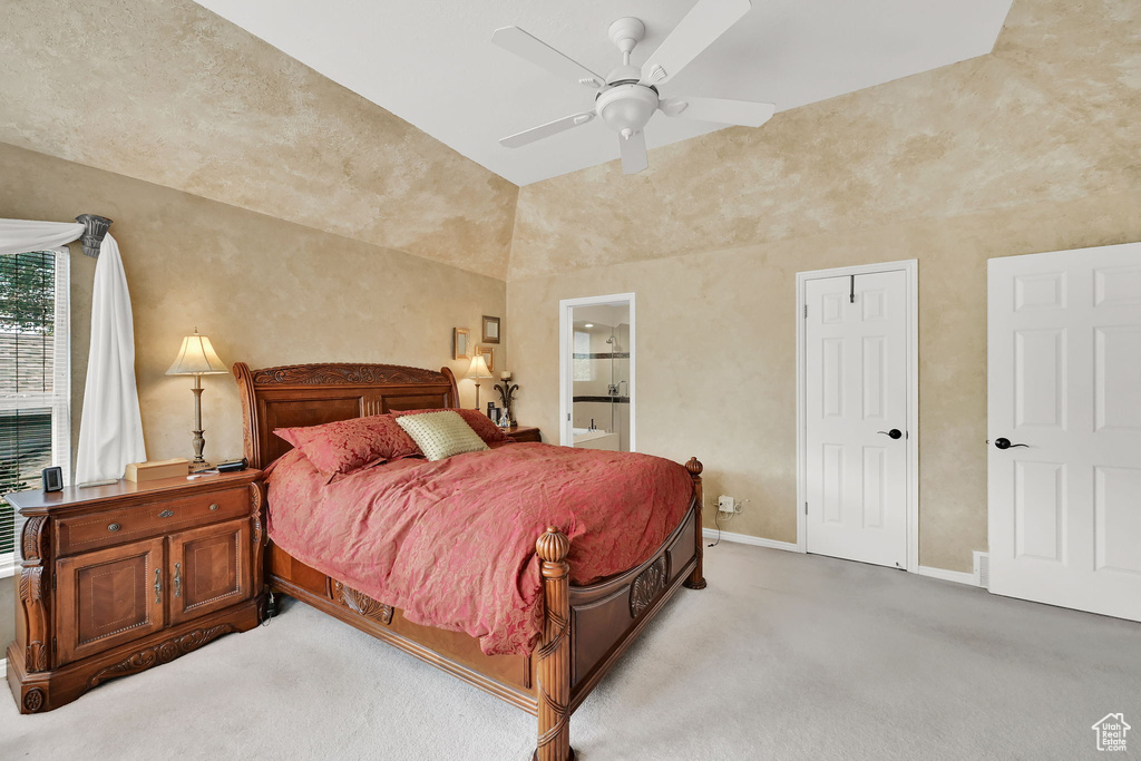 Carpeted bedroom featuring ensuite bath, ceiling fan, and lofted ceiling