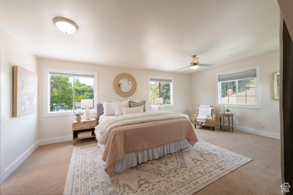 Bedroom with multiple windows, light carpet, and a ceiling fan