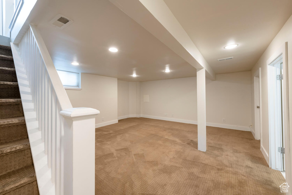 Below grade area with light carpet, stairs, and recessed lighting