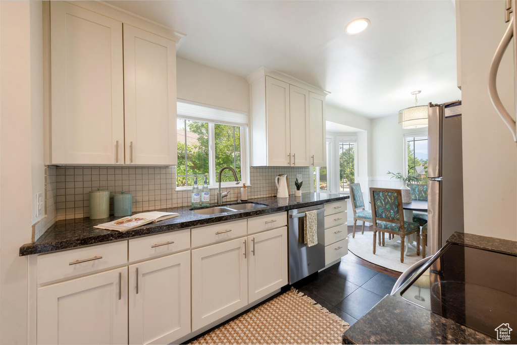 Kitchen with stainless steel appliances, tasteful backsplash, white cabinets, dark stone countertops, and recessed lighting