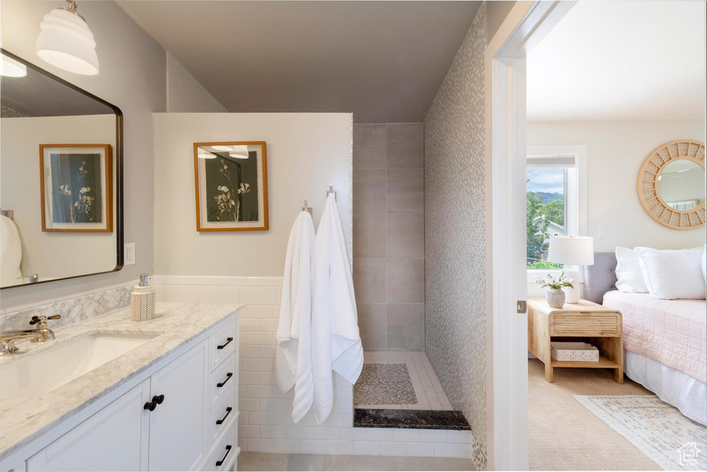 Full bathroom featuring ensuite bath, vanity, tiled shower, and tile walls