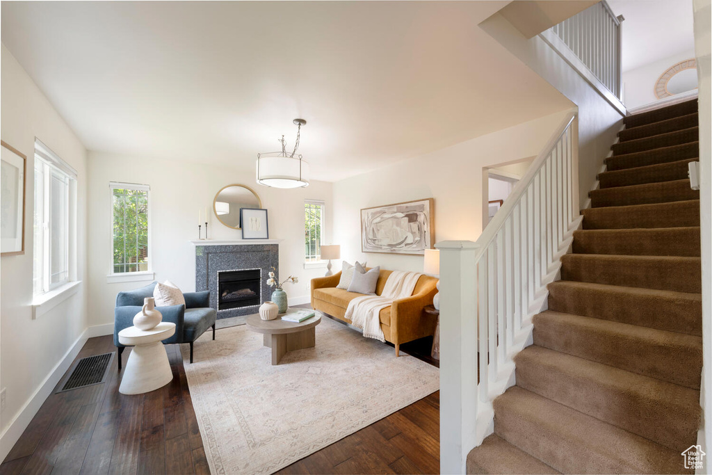 Living room featuring stairs, dark wood-style flooring, healthy amount of natural light, and a fireplace