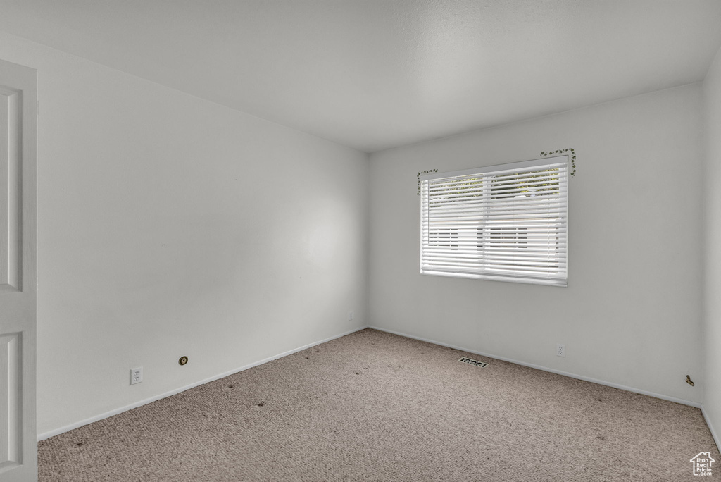 Empty room featuring carpet flooring and baseboards