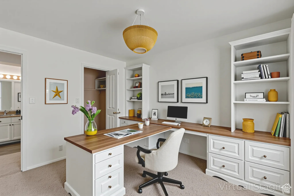 Office space featuring built in study area, light colored carpet, and built in shelves