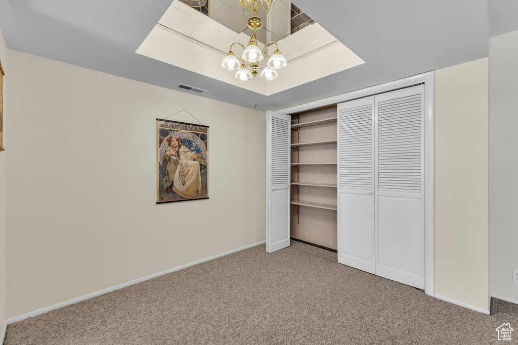 Unfurnished bedroom featuring carpet flooring, a chandelier, and a closet