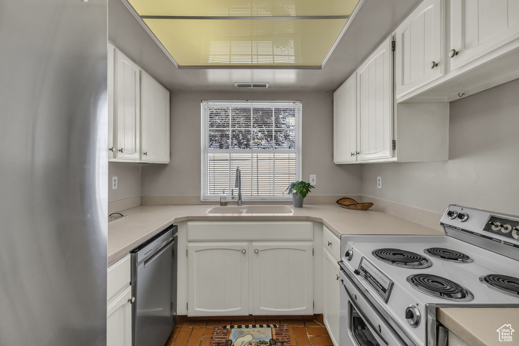 Kitchen with appliances with stainless steel finishes, white cabinets, and light countertops