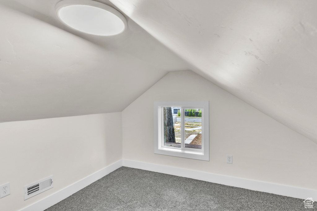 Bonus room featuring dark carpet and vaulted ceiling