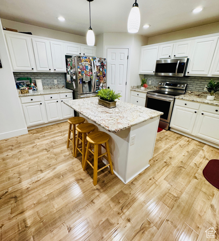 Kitchen featuring appliances with stainless steel finishes, backsplash, pendant lighting, white cabinets, and recessed lighting