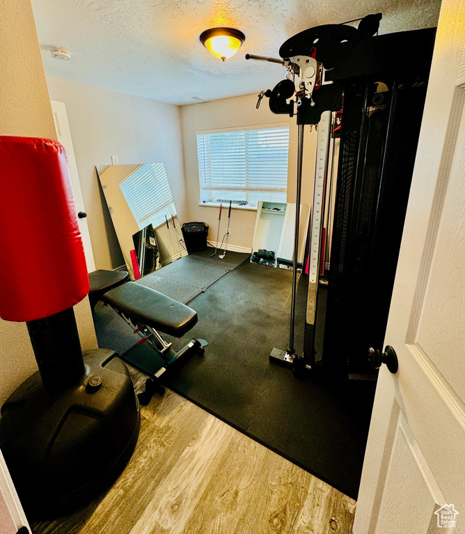 Exercise area with a textured ceiling and wood finished floors