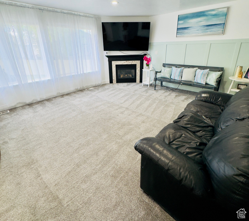 Carpeted living room featuring a decorative wall, a wainscoted wall, and a glass covered fireplace