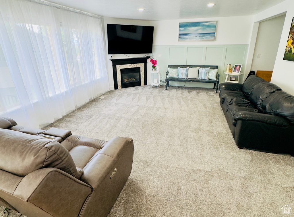 Carpeted living area with wainscoting, a glass covered fireplace, recessed lighting, and a decorative wall