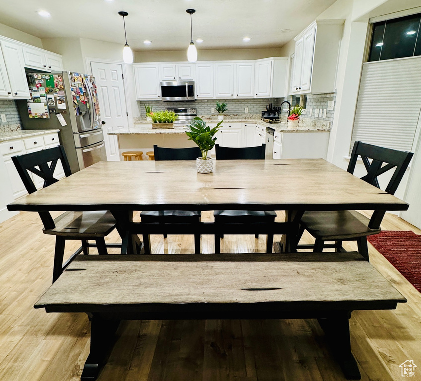 Dining room with light wood finished floors and recessed lighting