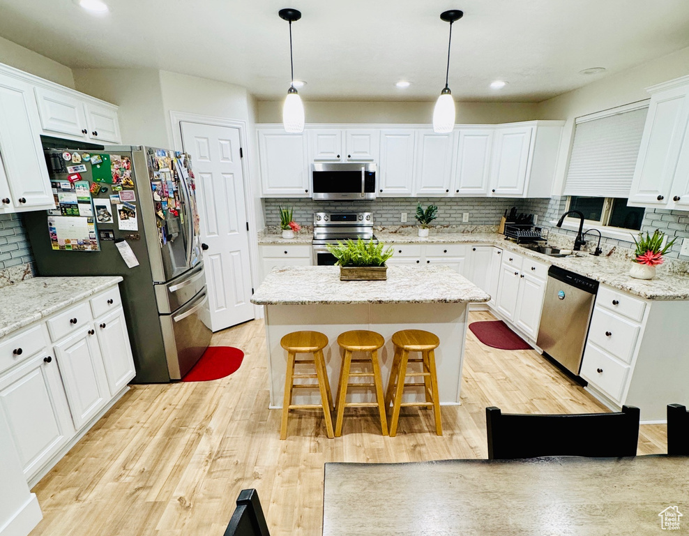 Kitchen with stainless steel appliances, a kitchen island, tasteful backsplash, white cabinetry, and recessed lighting
