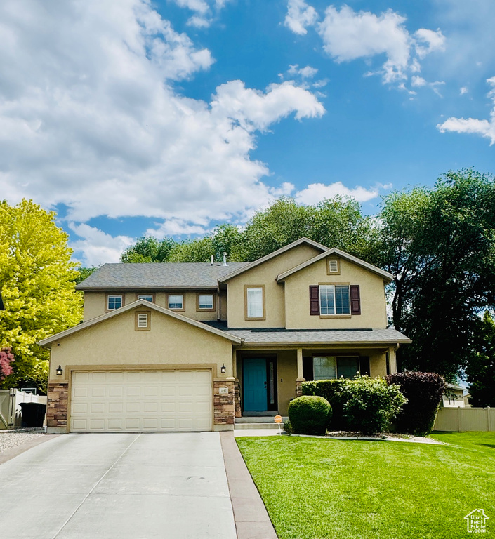 View of front of property featuring stucco siding, concrete driveway, a garage, stone siding, and a porch
