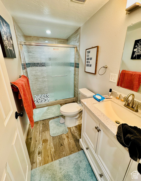 Bathroom featuring wood finished floors, a shower stall, vanity, and a textured ceiling