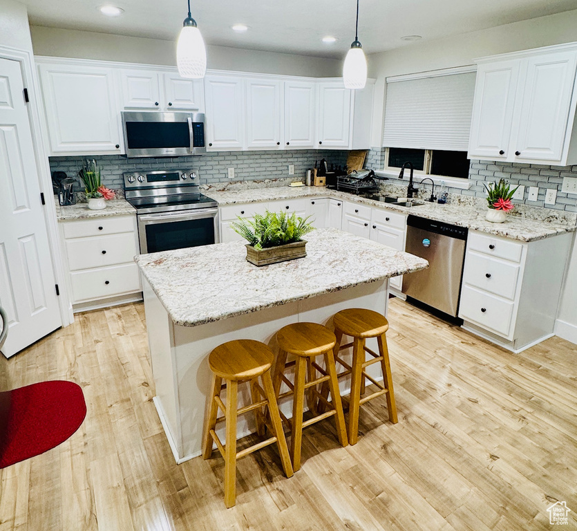 Kitchen featuring stainless steel appliances, tasteful backsplash, white cabinetry, and recessed lighting