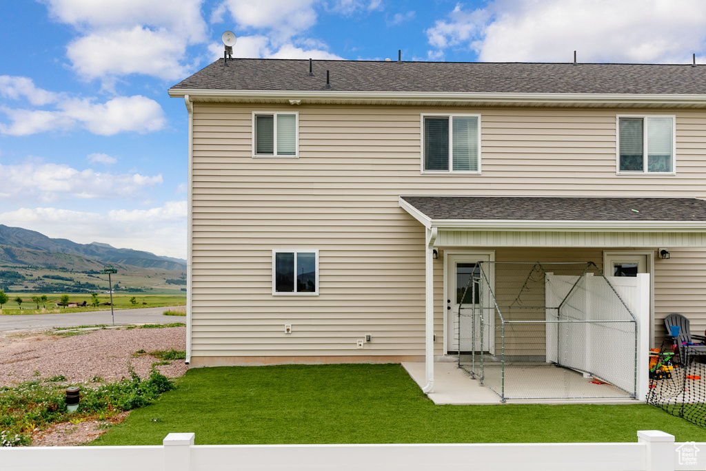 Rear view of property with a patio, a mountain view, and a yard