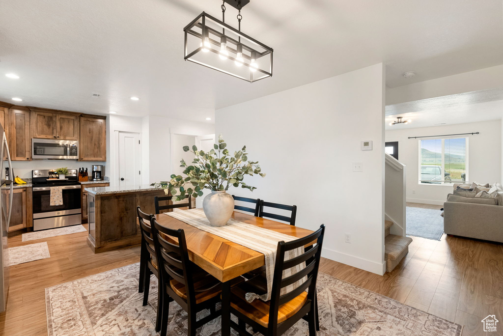 Dining area with light wood finished floors, stairway, and recessed lighting