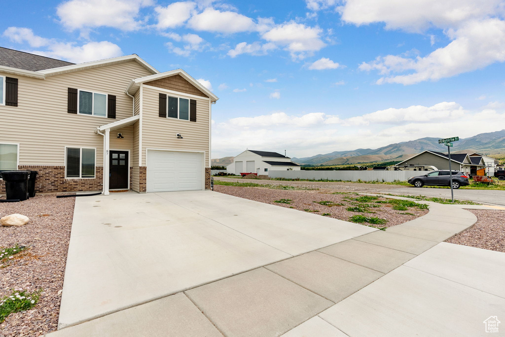 View of property exterior featuring a mountain view, a garage, concrete driveway, and brick siding