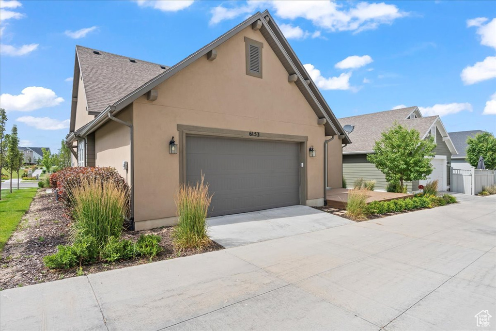 View of front of home with a garage, stucco siding, and driveway