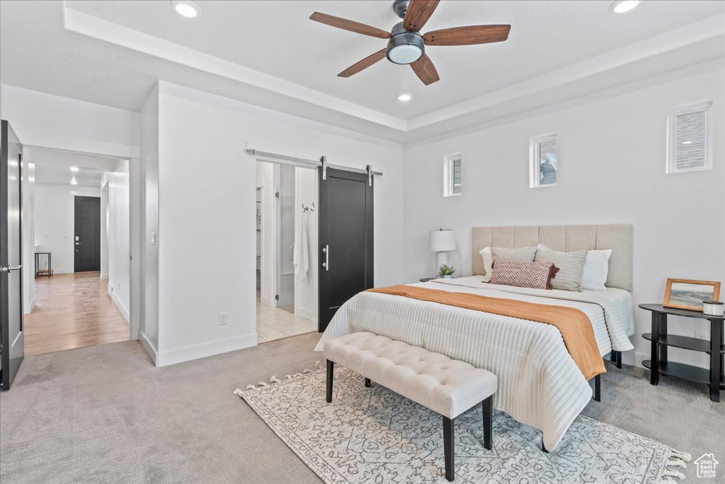 Bedroom featuring a barn door, recessed lighting, light colored carpet, a raised ceiling, and a ceiling fan