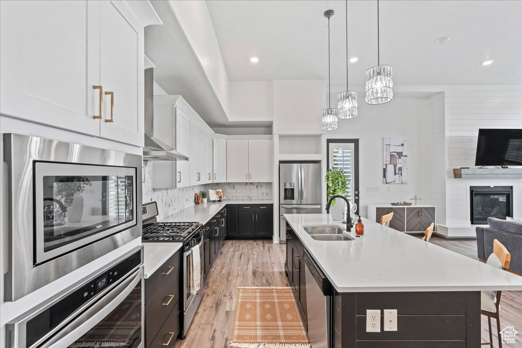 Kitchen with stainless steel appliances, open floor plan, white cabinets, light countertops, and recessed lighting