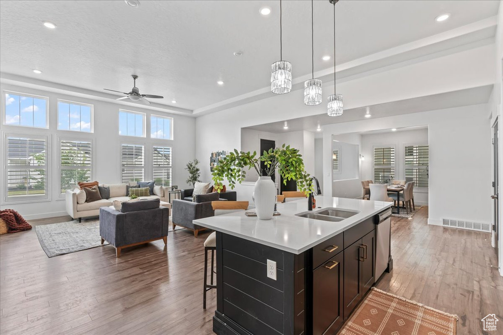 Kitchen with light wood-style flooring, light countertops, dishwasher, open floor plan, and a kitchen island with sink