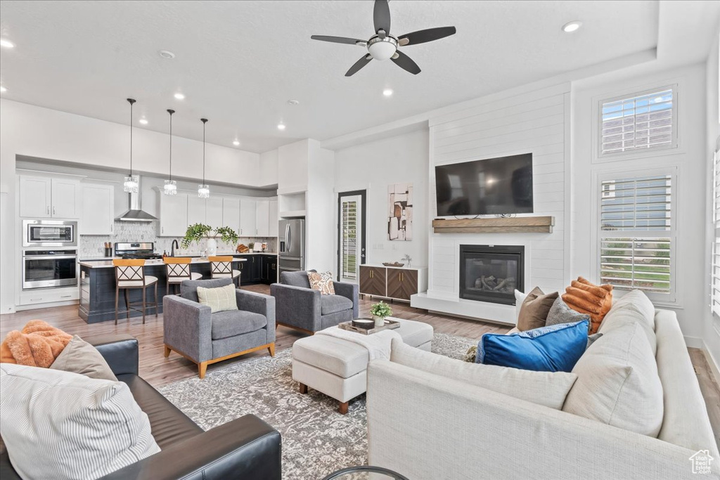 Living area featuring light wood finished floors, recessed lighting, a fireplace, and ceiling fan