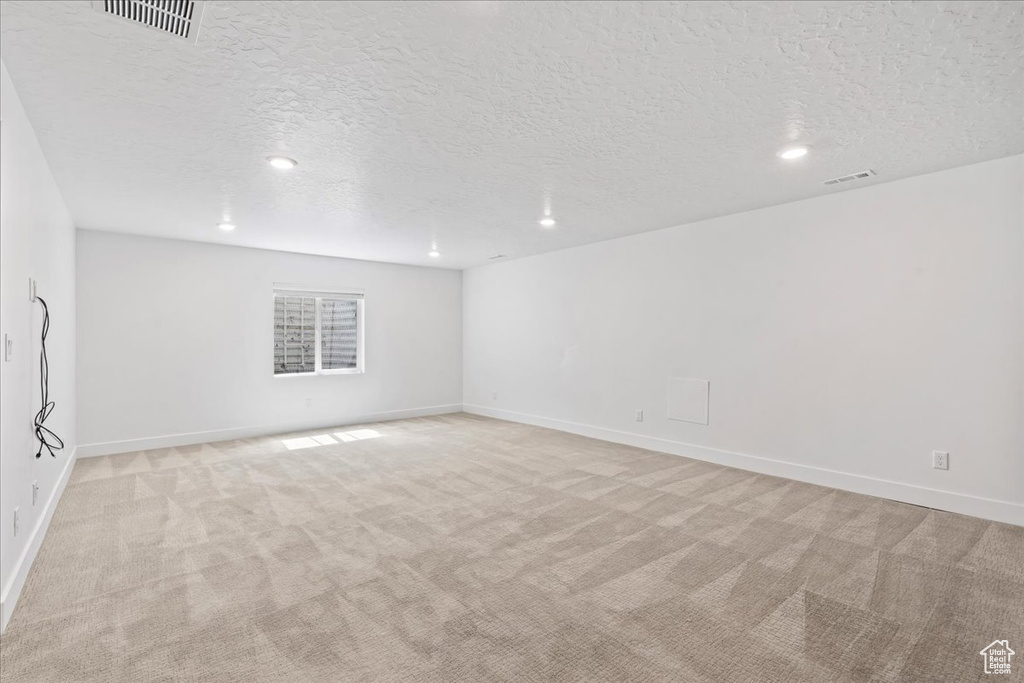 Spare room featuring light colored carpet, a textured ceiling, and recessed lighting