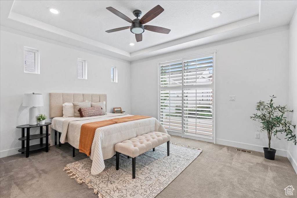 Bedroom with a tray ceiling, light colored carpet, recessed lighting, and ceiling fan