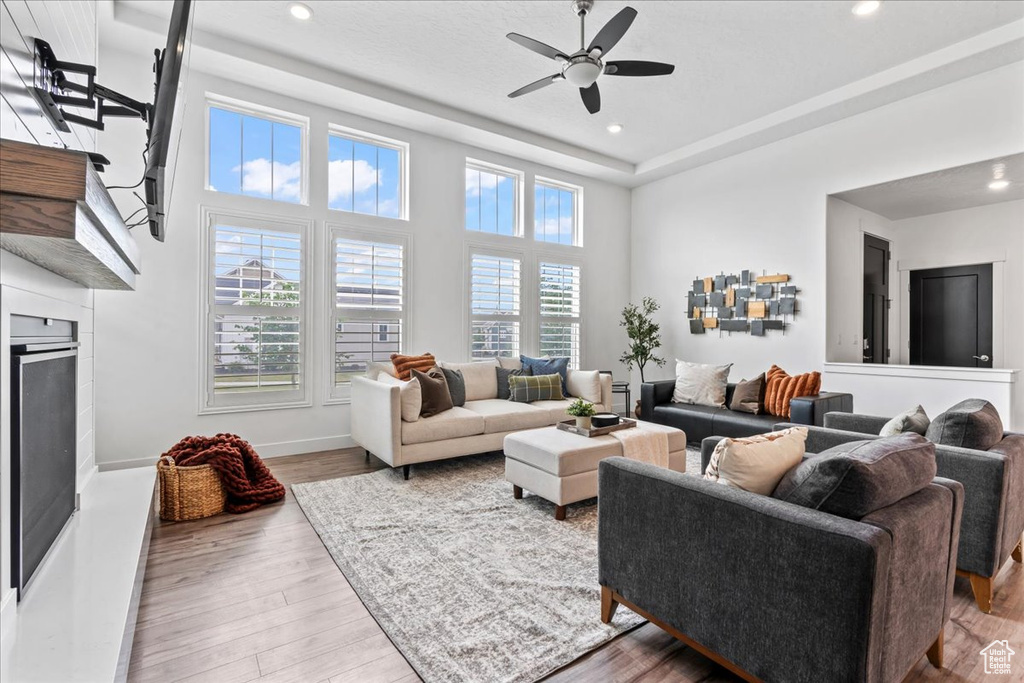 Living area featuring wood finished floors, recessed lighting, a ceiling fan, and a tray ceiling