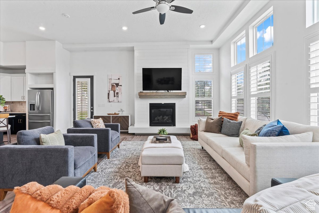 Living room with wood finished floors, a ceiling fan, recessed lighting, and a large fireplace