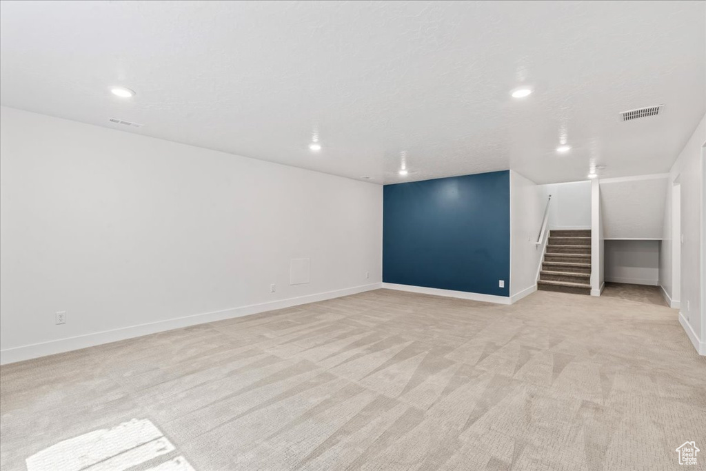 Finished basement featuring light colored carpet, stairs, and recessed lighting