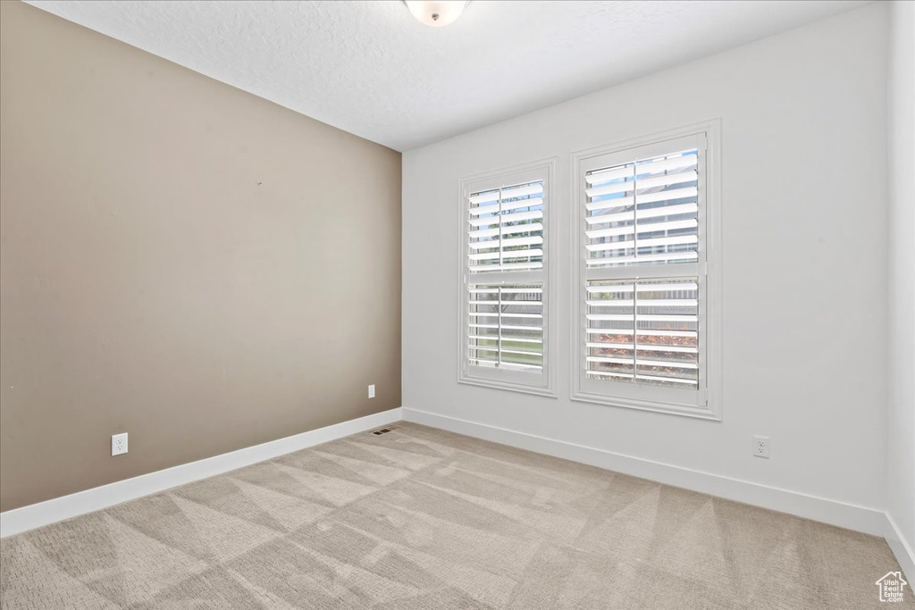 Spare room with light carpet and a textured ceiling