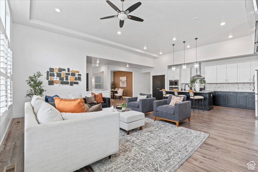 Living area with ceiling fan, light wood finished floors, and recessed lighting