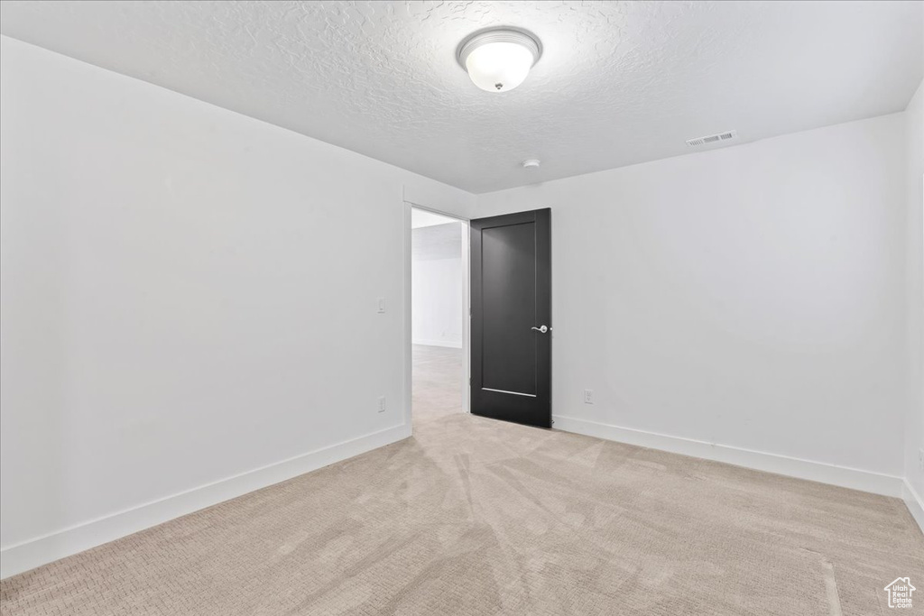 Spare room featuring a textured ceiling and light carpet