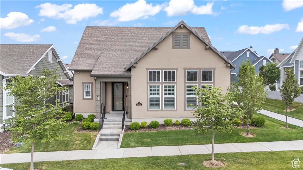 View of front of house featuring stucco siding, a front lawn, and a shingled roof