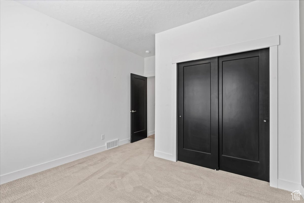 Unfurnished bedroom with carpet flooring, a textured ceiling, and a closet