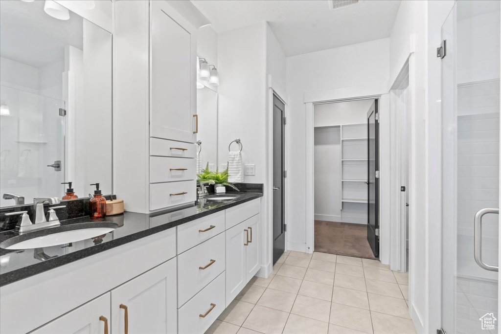 Bathroom with a shower stall, double vanity, a spacious closet, and tile patterned floors