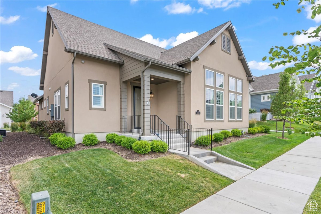 View of front of property with stucco siding, roof with shingles, and a front lawn