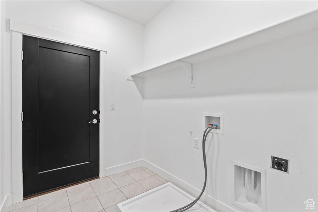 Washroom with hookup for a washing machine, light tile patterned floors, and electric dryer hookup