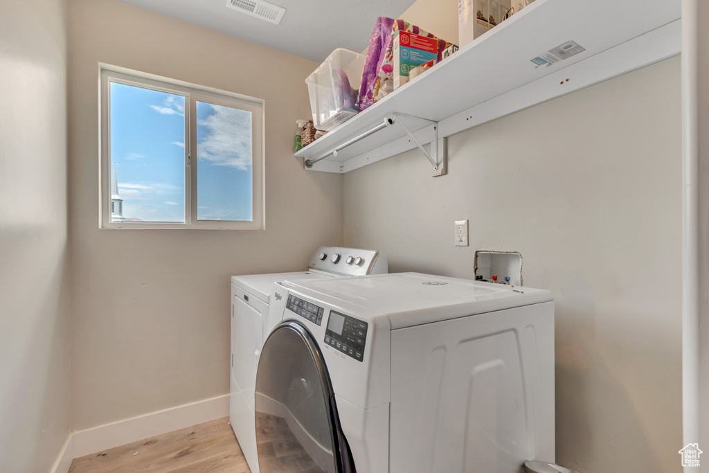 Washroom featuring light wood-style floors and separate washer and dryer