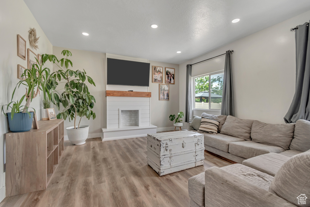 Living room featuring a fireplace, light wood-style flooring, and recessed lighting